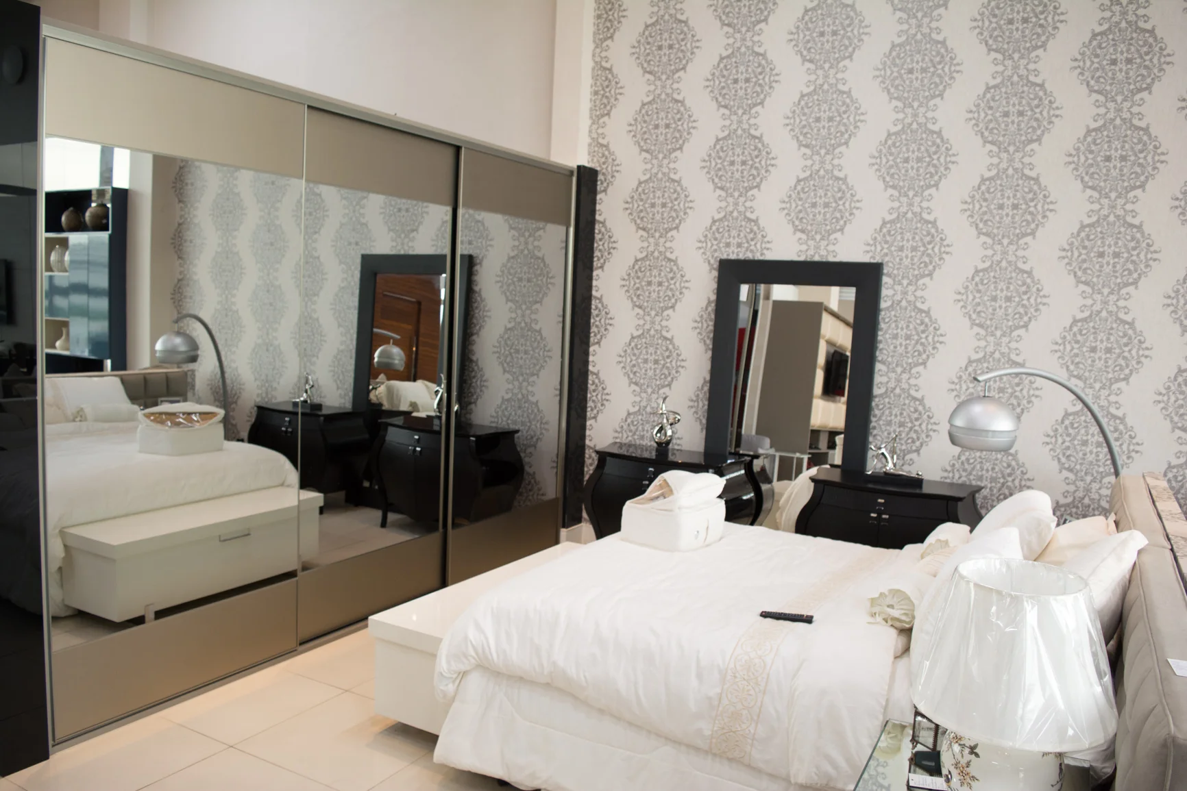 Dormitório com espelhos, cama clara e mobiliário